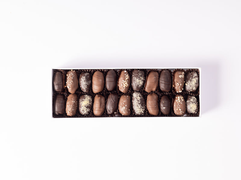 Luxury assortment of stuffed dates with ashta, hazelnut, nut praline, and mastique fillings, coated in milk and dark chocolate.